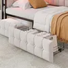A close-up view of a beige upholstered daybed with storage drawers pulled out, revealing folded linens and other items. Podgląd zdjęcia produktu