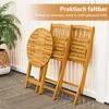 A wooden bistro table and two chairs are folded and leaning against a white railing on a patio. Náhled obrázku produktu