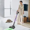 A woman is vacuuming a carpeted floor in a modern living room, with a cat lying nearby. Anteprima dell’immagine prodotto