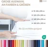 A hand is shown pressing down on a white sheet, indicating its size and fit. Various color swatches are displayed at the bottom. Produktbild-Vorschau