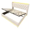 A white upholstered bed frame with its slatted base lifted to reveal storage space underneath. Yellow LED lighting is integrated into the headboard and frame. Produktbild-Vorschau