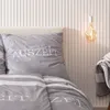 A close-up view of bedding with a striped pattern and text. Produktbild-Vorschau