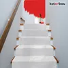 A staircase with white carpet runners, a bucket of red paint, and a paint roller at the top. Náhľad obrázku produktu