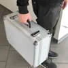 A person is holding a silver briefcase. Produktbild-Vorschau