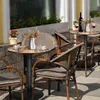 An outdoor cafe setting with tables and chairs. Produktbild-Vorschau