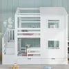 A white bunk bed designed like a house, with stairs and storage drawers, set against a light blue wall with wall decals. Produktbild-Vorschau