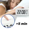 A person sleeping next to a digital alarm clock, with a close-up inset showing a finger pressing the snooze button. Voir les images du produit