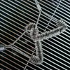 A grill brush cleaning a grill grate. Produktbild-Vorschau