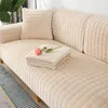 A close-up view of a beige sofa with a textured cover, featuring a folded blanket and a single pink rose. Náhled obrázku produktu