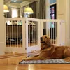 A golden retriever dog lies on a mat in front of a white pet gate in a well-lit room. Produktbild-Vorschau