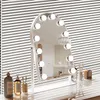 A vanity mirror with lights on a dresser, with toiletries and decorative items. Produktbild-Vorschau