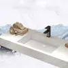 A white ceramic sink with a black faucet on a marble countertop, with towels and perfume bottles on the side. The background depicts a snowy mountain landscape. Anteprima dell’immagine prodotto