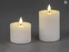 Two white LED candles with ribbed texture and flickering LED flames are displayed against a plain gray background. Produktbild-Vorschau