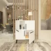 A white cabinet with black handles is placed in a room with a wooden partition and a large abstract painting on the wall. Dining chairs and a table are visible in the background. Produktbild-Vorschau