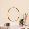 A round wooden mirror is displayed on a wall above a white dresser, with decorative items like a candle and plants on the dresser. Voir les images du produit