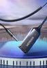 A close-up shot of a Ugreen Bluetooth audio adapter and a 3.5mm audio jack, placed on a stage with a piano keyboard base and a background resembling sound waves and a sky. Náhľad obrázku produktu
