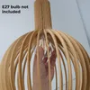 A hand is shown inserting a light bulb into a wooden pendant lamp. Voir les images du produit
