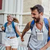 A couple is running and holding hands, appearing excited, with the man and woman both wearing small white devices around their necks. Produktbild-Vorschau