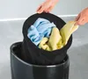 Hands are shown placing laundry into a black laundry hamper. Produktbild-Vorschau