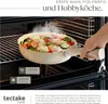 A hand is holding a cooking pot filled with food inside an oven. Produktbild-Vorschau