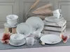 A collection of white porcelain dinnerware with a magnolia flower design, arranged on a gray surface with decorative elements. Náhľad obrázku produktu