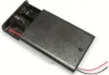 A black plastic battery holder with two AA batteries inserted, showing red and black wires extending from the end. Produktbild-Vorschau