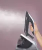A hand holding a steam iron that is emitting steam. Voir les images du produit