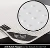 A close-up of a white mattress protector with anti-slip nubs on the back, and a brand label. Produktbild-Vorschau