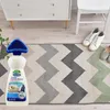 A cleaning product with a brush attachment is placed on a rug in front of a dresser and a chair. Shoes are also visible on the rug. Podgląd zdjęcia produktu