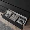A close-up view of an open drawer in a black dresser, revealing folded t-shirts. Náhľad obrázku produktu