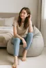 A woman sits on a beanbag chair in a bedroom. Produktbild-Vorschau