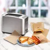 A toaster and sandwich bags with toasted sandwiches are displayed on a marble countertop with a blurred window in the background. Produktbild-Vorschau