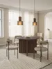A dining room scene with a round wooden table and chairs, illuminated by pendant lights. Produktbild-Vorschau