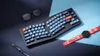 A keyboard, glasses, a pen, and a smartwatch are arranged on a dark and light blue surface. Anteprima dell’immagine prodotto