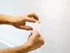 A person's hands are shown applying a bandage to a textured white wall. Anteprima dell’immagine prodotto