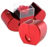 Rote apfelförmige Geschenkbox, teilweise geöffnet, mit einer roten konservierten Rose in einer durchsichtigen Hülle und einer kleinen herzförmigen Schublade Anteprima dell’immagine prodotto