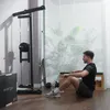 A man is performing a rowing exercise using a cable machine in a home gym setting. Produktbild-Vorschau