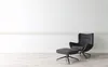 A modern armchair and ottoman set against a plain white wall and light wooden floor. Náhľad obrázku produktu
