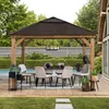 An outdoor dining set under a wooden gazebo with a dark roof, surrounded by greenery and a pool. Produktbild-Vorschau