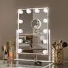 A vanity mirror with lights and makeup brushes on a dresser. Podgląd zdjęcia produktu