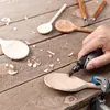 A person is using a Dremel tool to carve a wooden spoon on a wooden table. Anteprima dell’immagine prodotto