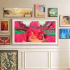A collection of framed artwork displayed on a wall above a white wainscoting. Produktbild-Vorschau