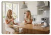 Two women are sitting at a kitchen island, drinking coffee and talking. A coffee machine is on the counter. Anteprima dell’immagine prodotto