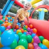 A young boy is playing in a ball pit filled with colorful balls. Voir les images du produit