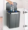 A hand is placing a plastic bottle into a gray trash can that is hanging inside a cabinet door. Anteprima dell’immagine prodotto
