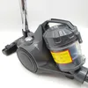 Close-up of a gray cylinder vacuum cleaner with a transparent dustbin and a yellow warning label. Anteprima dell’immagine prodotto