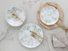 A table setting with plates, cutlery, and a napkin, arranged on a wooden board and a grey surface, with dried plant sprigs. Náhľad obrázku produktu