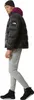 A man wearing a black beanie, a black puffer jacket with a purple hood, and gray sweatpants, posing against a white background. Produktbild-Vorschau