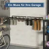 A garage wall with boot racks holding several pairs of boots, a bicycle, and tools. A promotional banner is across the top. Produktbild-Vorschau