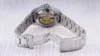 The back of a watch with its clasp open, resting on a light-colored wooden surface. Náhled obrázku produktu